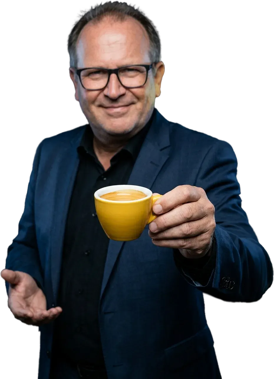 Stefan Porciello reicht lächelnd eine gelbe Espressotasse entgegen